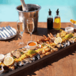 Sharing platter on a table with champagne next to a swimming pool