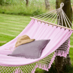 a pink woven hammock with a summer hat on it